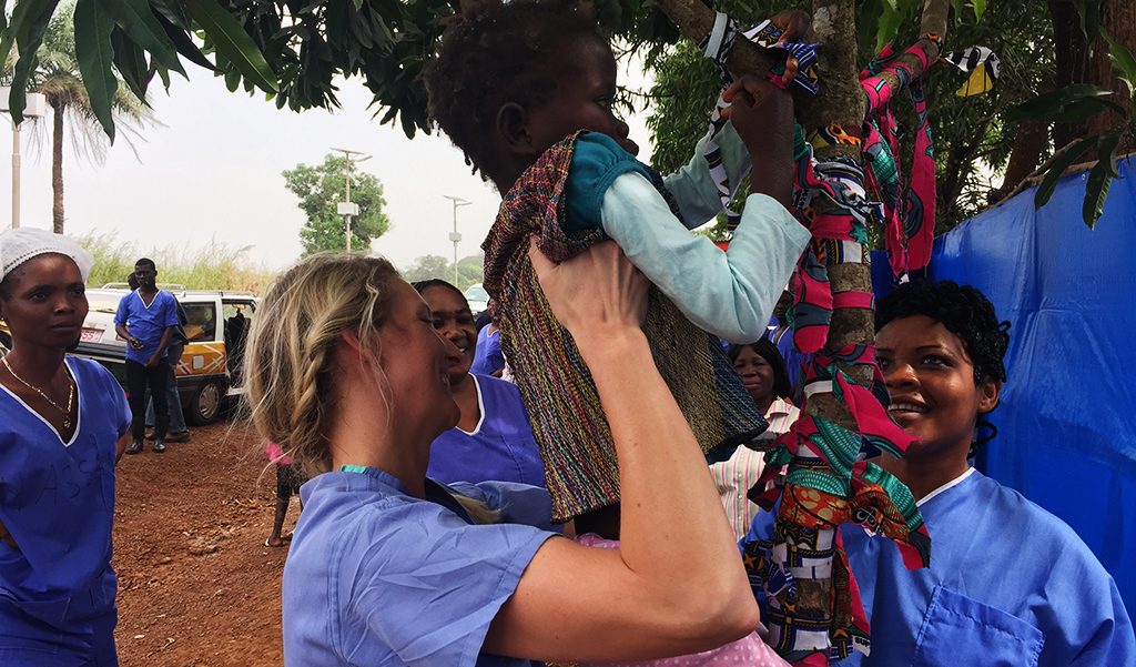 Dani Kloepper holds up an Ebola survivor at the Survivor Tree