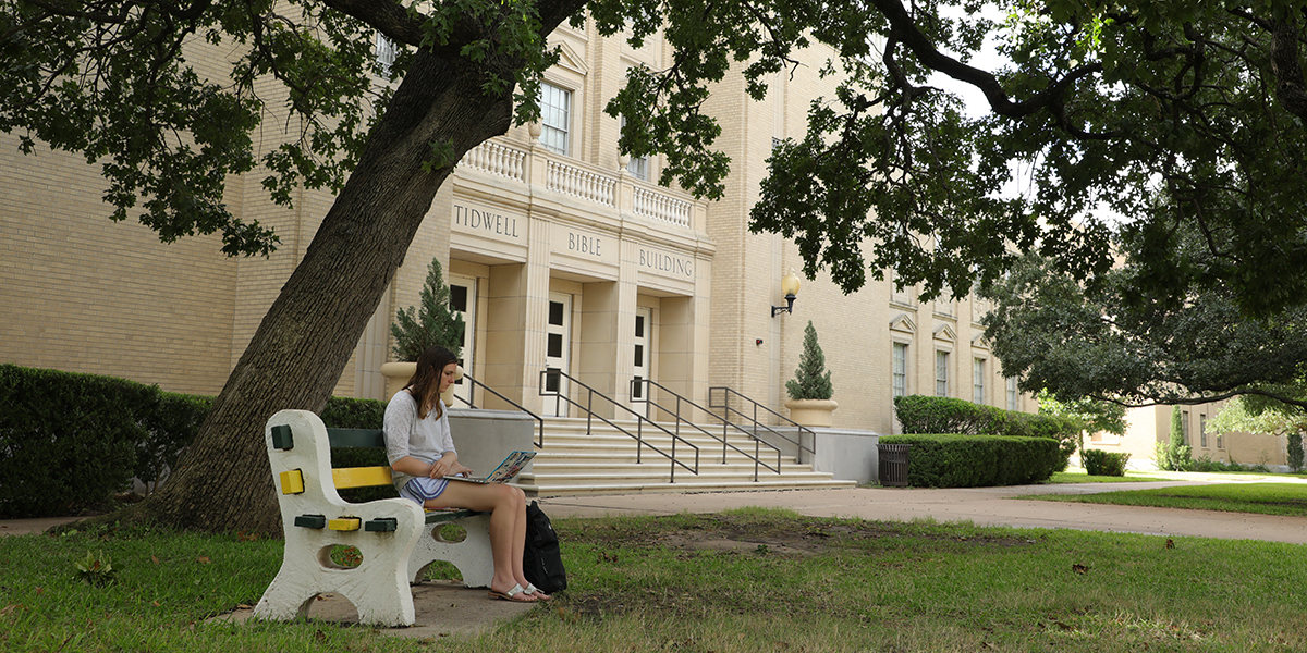 A student sitting outside Tidwell Bible Building