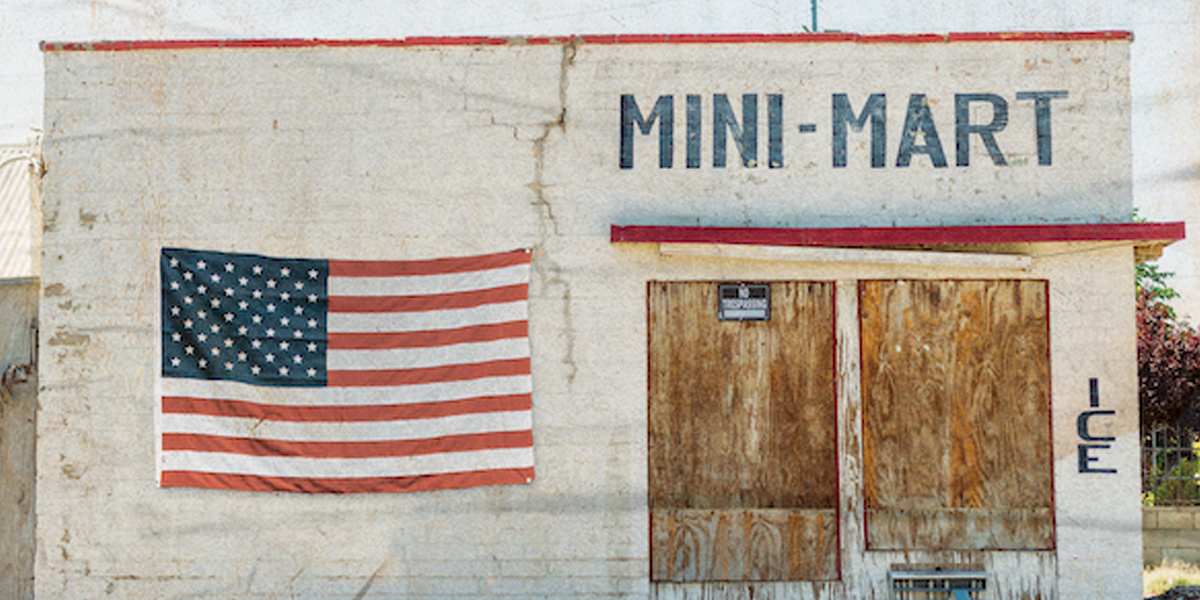 A boarded up mini-mart with an American flag hanging out front