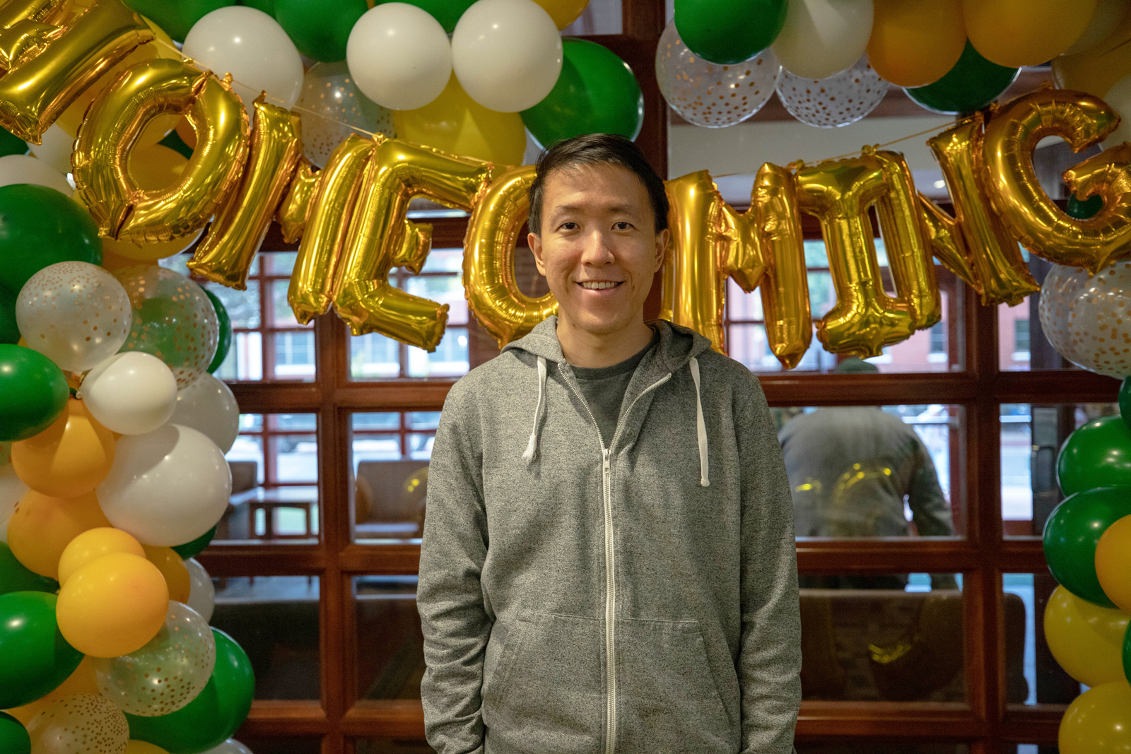 Daniel Kiang in front of green and gold balloons