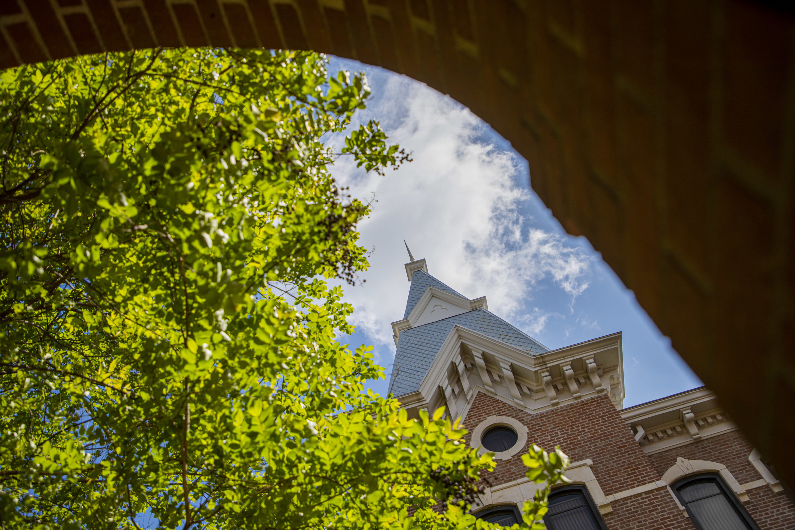 An Old Main spire, viewed through a Burleson Quad archway