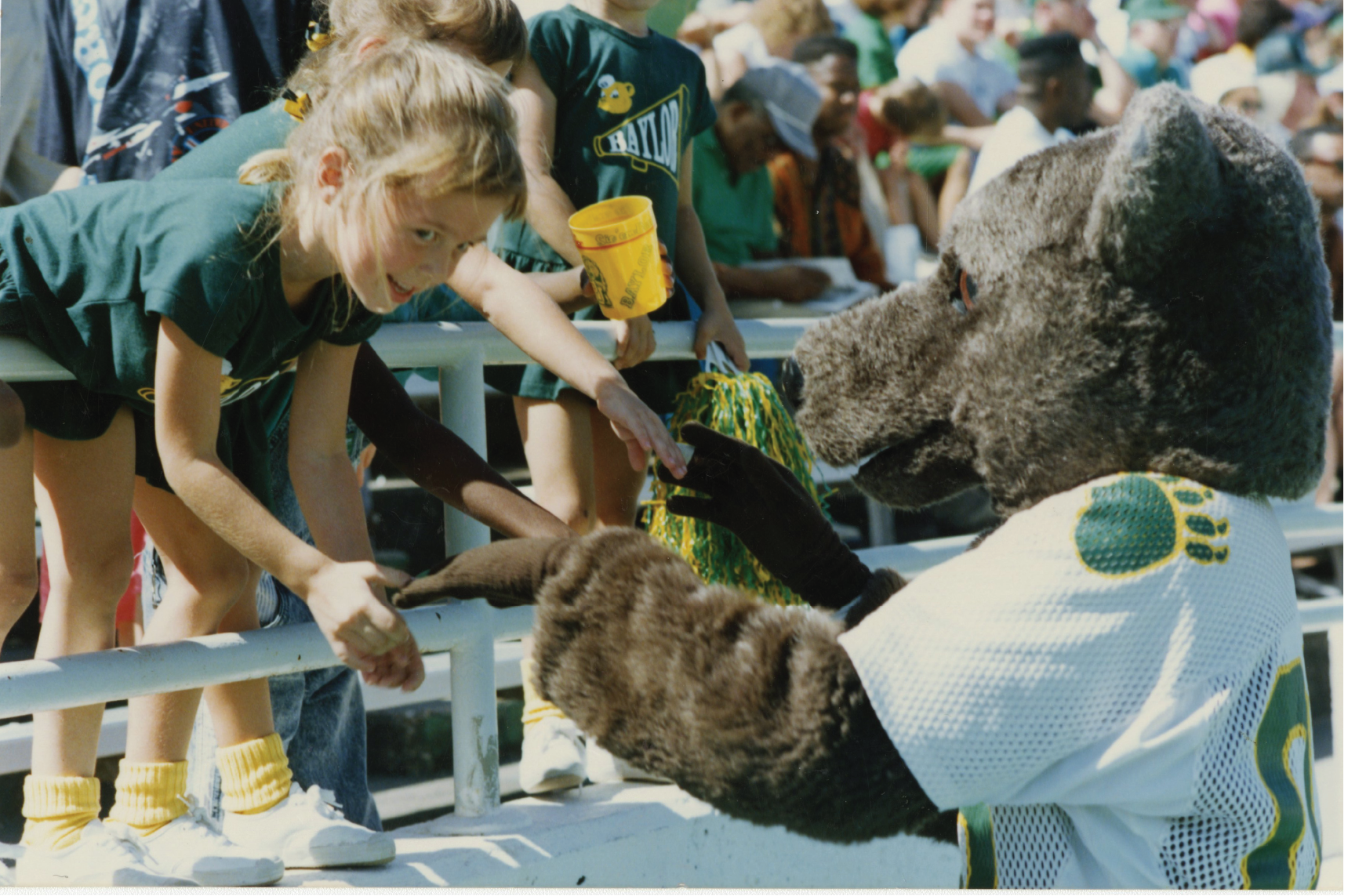 A costumed Bear mascot interacts with a young fan