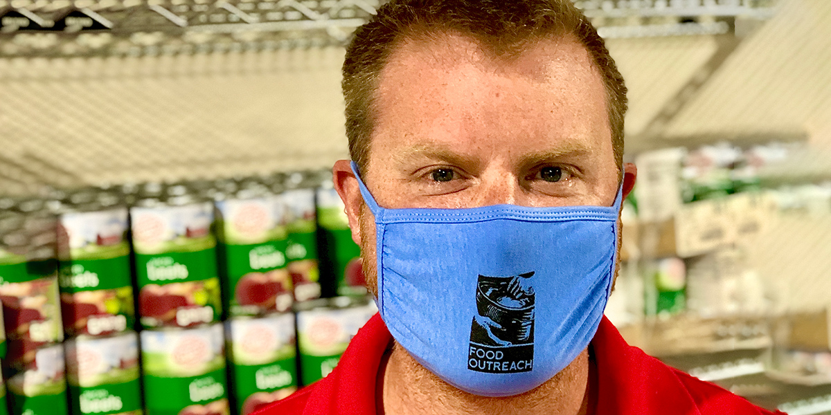 Justin Kralemann posing with a mask on in the food pantry