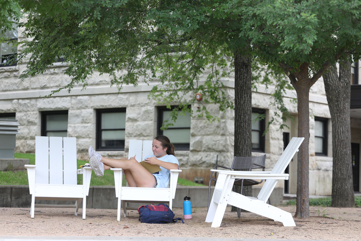 A student sitting in a new Adirondack chair on campus