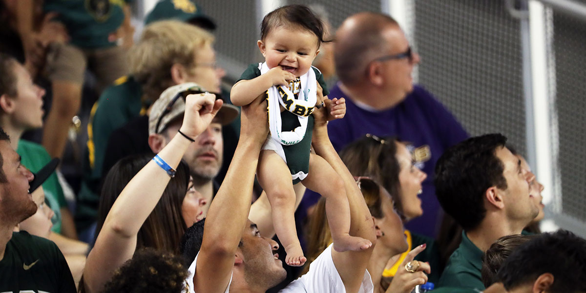 A baby held up in the crowd at McLane Stadium