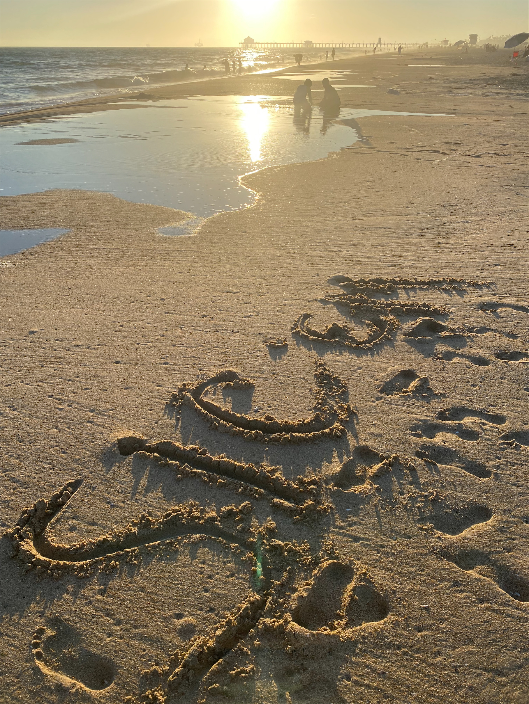 "Sic 'em" carved in the beach sand at sunset
