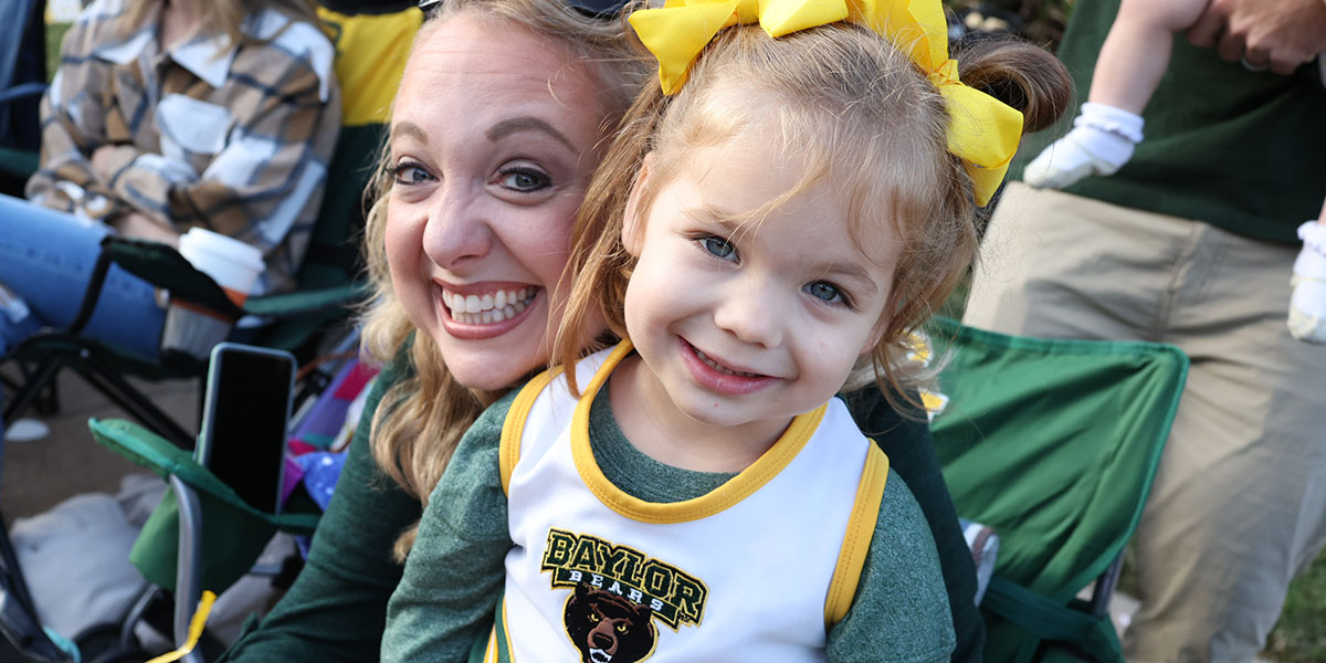 A mother and daughter smile at the Homecoming parade