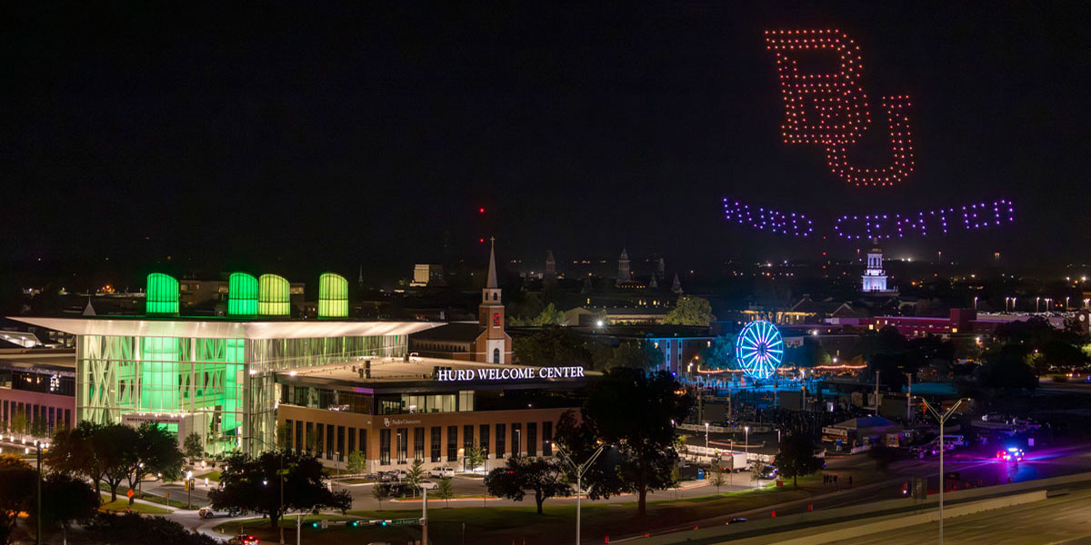 Drones over the Hurd Welcome Center form a BU logo