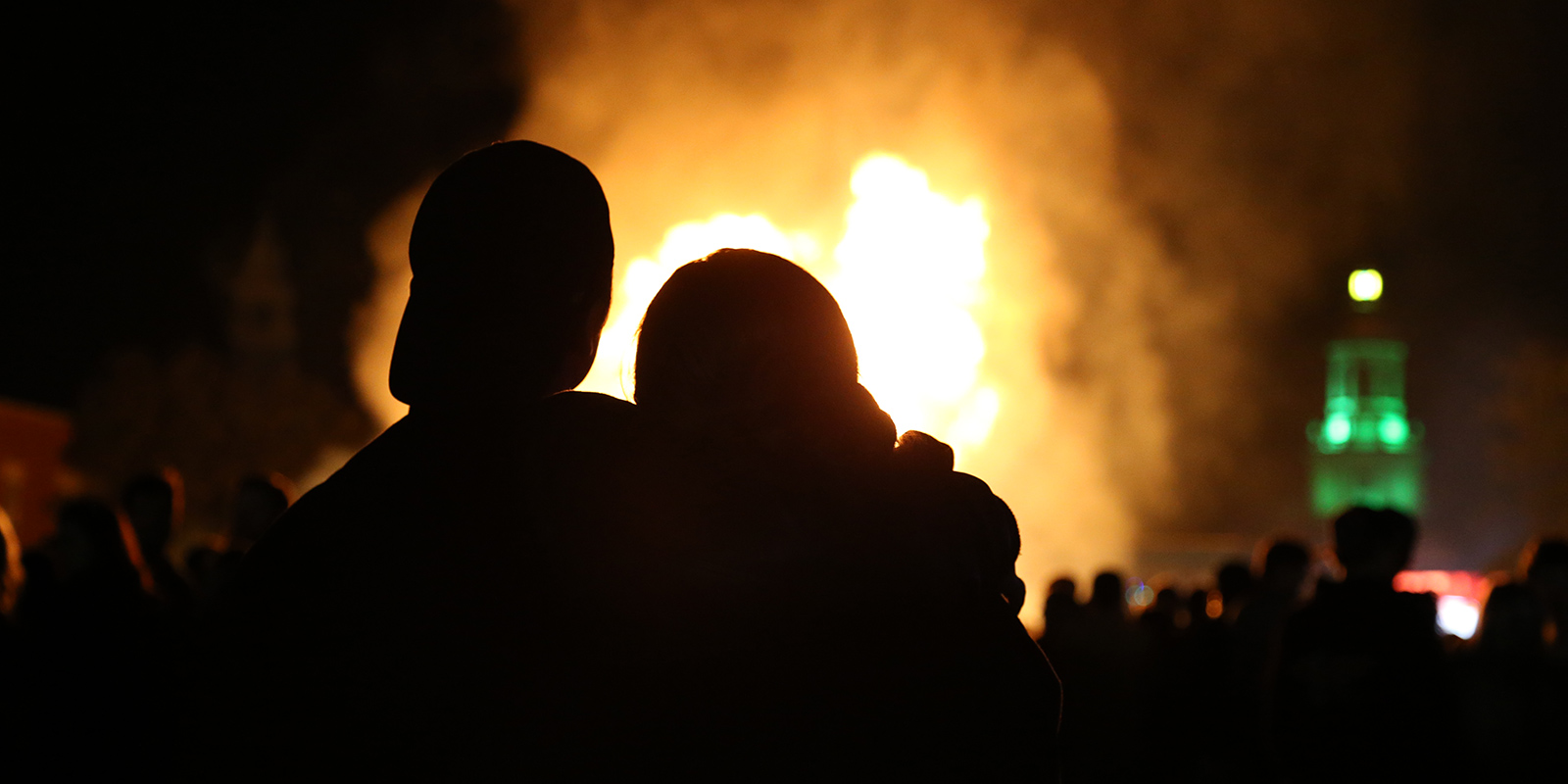 Silhouettes of two people in front of the Homecoming bonfire