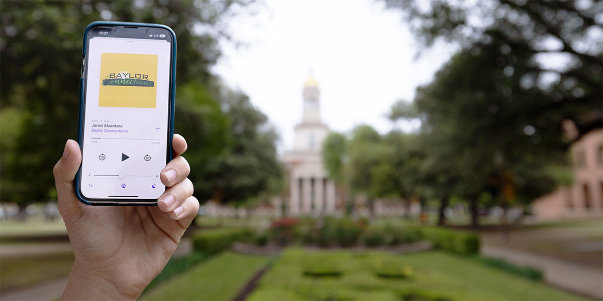 A phone playing "Baylor Connections" held up outside Pat Neff Hall