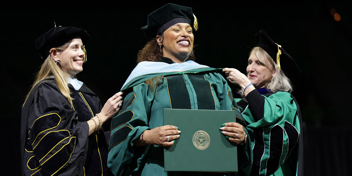 A graduate student receives her hood at Commencement