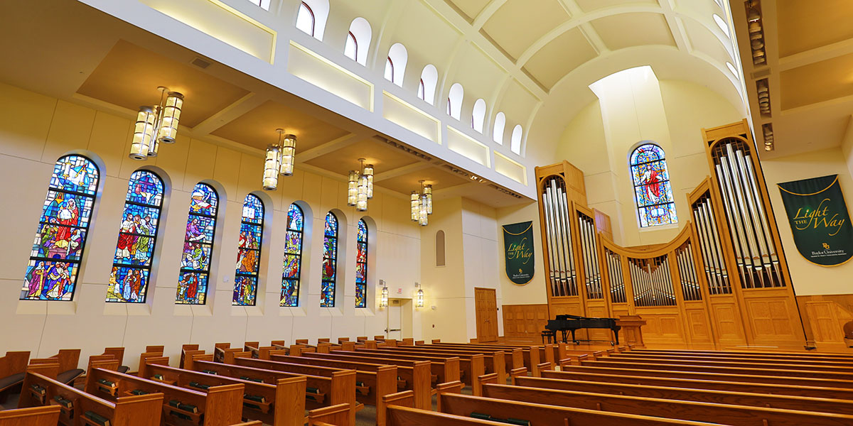 Interior of Powell Chapel, with wooden pews and stained glass windows