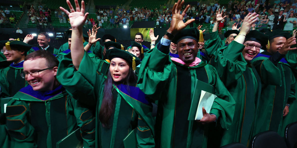 Doctoral graduates doing a sic 'em at Commencement