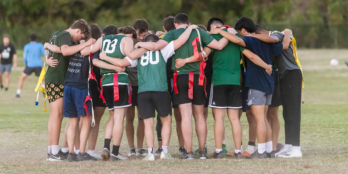 Students huddle during a flag football game