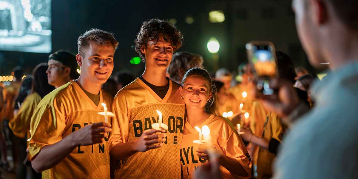 Baylor freshmen hold candles as they pose for a photo