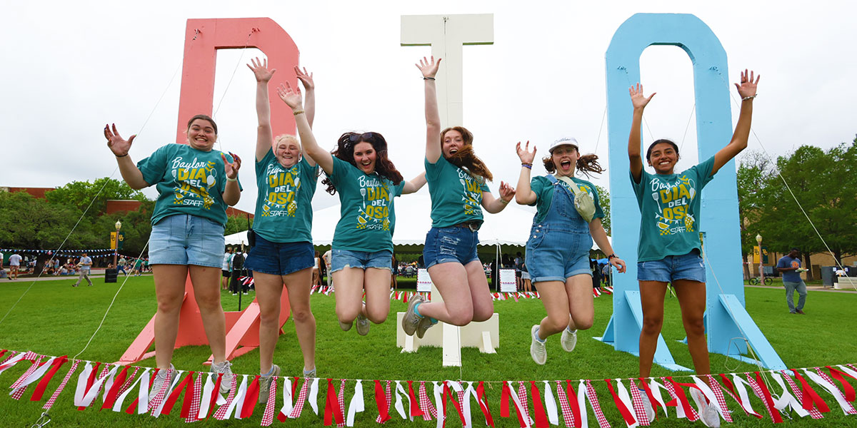 Students jump in front of the large "DIA" letters on Fountain Mall