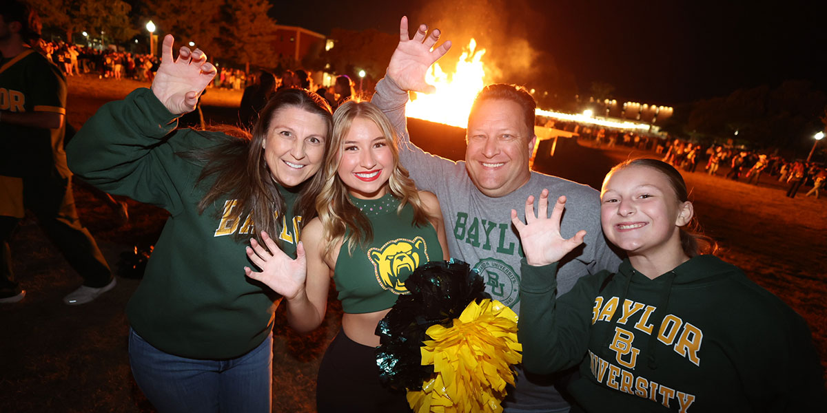 A family does a sic 'em in front of the Homecoming bonfire
