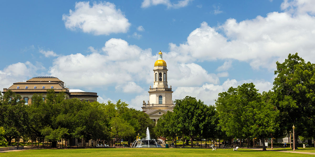 Pat Neff Hall towers over Fountain Mall against a sky of blue with white clouds